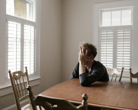 photo of man leaning on wooden table