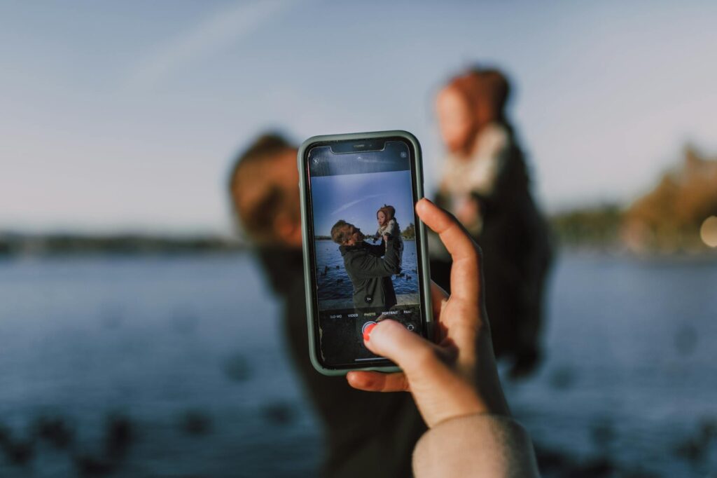 person taking photo of man carrying a baby