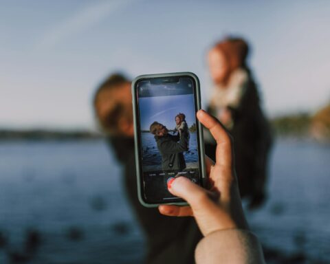 person taking photo of man carrying a baby