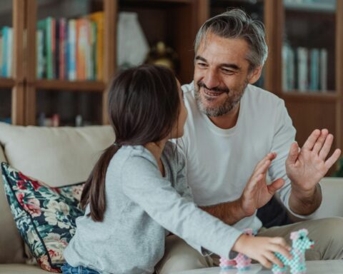 a girl holding toys while looking at her smiling father