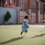 little girls running around a court in superhero capes